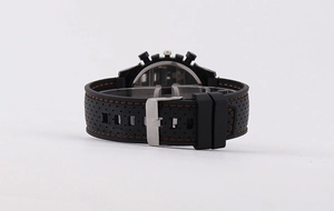 Detail of black silicone watch strap with orange stitching and silver metal buckle