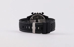 Detail of black silicone watch strap with silver buckle and white stitching accents
