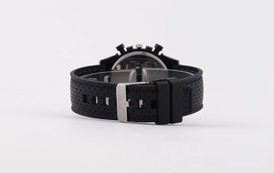 Detailed view of black silicone watch strap with blue stitching and silver metal buckle