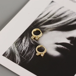 Detail of gold huggie hoop earrings with sparkling cubic zirconia stones