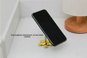 Gold suction cup phone holder with flexible arm supporting a black smartphone on a desk