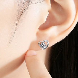Macro close-up of heart-shaped silver stud earring with sparkling cubic zirconia inlay