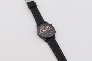 Close-up of black leather watch strap with white stitching and rose gold quartz dial