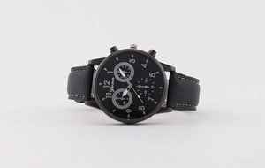 Detail view of black quartz watch with three sub-dials and white stitched leather strap