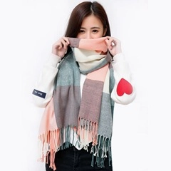 Detail of pink and grey plaid cashmere-like scarf with soft fringe edges on model