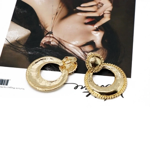 Detailed close-up of golden irregular hammer texture hoop earrings on a magazine background