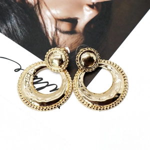 Close-up of golden round earrings featuring hammered texture and vintage gear edges