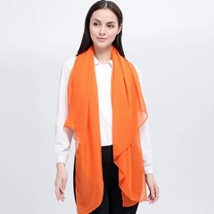 Detailed view of the sheer orange pashmina texture and soft material on a model