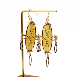 Close-up of golden drop earrings with yellow oval gemstones on a T-bar stand