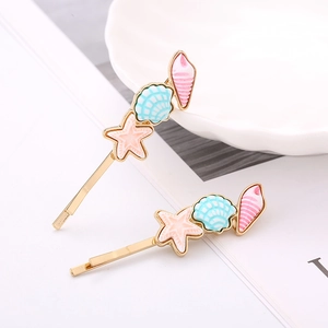 Golden ocean theme hair clips with starfish, shell, and conch charms on white book