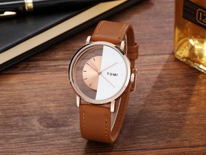 Detail of rose gold quartz watch with hollow design and brown leather strap on wooden desk