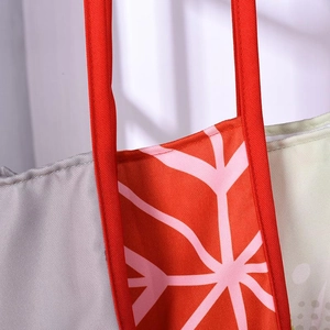 Détail des poignées rouges et des coutures sur le tablier de Noël en toile imprimée