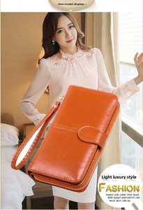 Detail view of the orange long wallet with double zipper and stylish hand strap