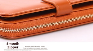 Macro shot of smooth gold-tone zipper teeth on an orange glossy leather long wallet