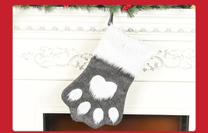 Grey felt Christmas stocking in paw shape hanging on white fireplace mantel decoration