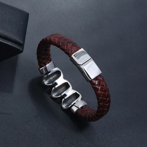 Close-up of brown braided leather bracelet with silver magnetic clasp on black background
