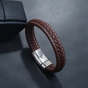 Détail du bracelet en cuir tressé marron avec surpiqûres et fermoir magnétique argenté