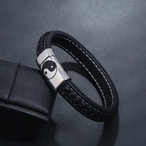 Détail du bracelet en cuir tressé noir avec fermoir argenté gravé d'un motif Yin Yang