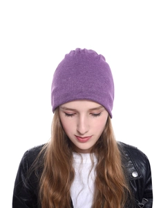 Dettaglio del berretto in maglia viola che mostra la trama fine e la vestibilità