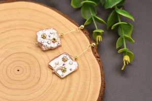 Close-up of vintage baroque pearl earrings with delicate floral crystal inlay details.