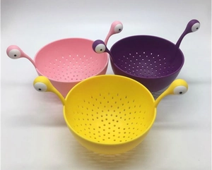 Three snail-shaped plastic colanders in pink, purple, and yellow with drainage holes