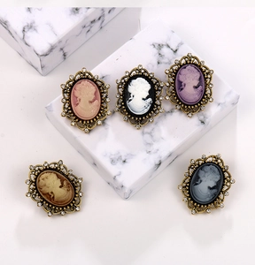 Detailed view of vintage cameo brooches with rhinestones on marble display pedestals