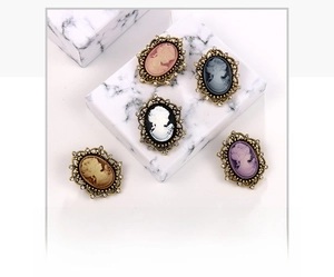Detailed view of five vintage queen portrait brooches with rhinestones on marble blocks