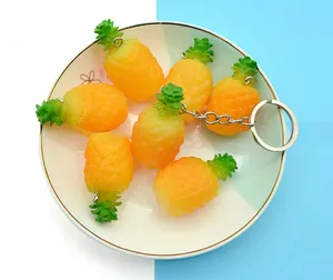 Close-up of realistic PVC mini pineapple keychains in a white ceramic bowl