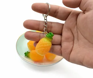 Detailed view of a realistic PVC pineapple keychain with bright yellow texture and metal ring