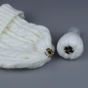 White knitted beanie with a detachable raccoon fur pom pom and secure metal snap button