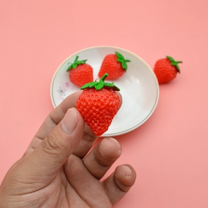 Realistic PVC strawberry keychain pendant featuring textured fruit skin and green leaves