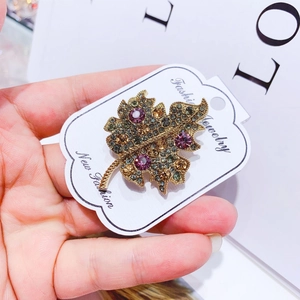 Elegant maple leaf brooch in gold alloy with purple and amber rhinestones on card