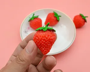 Close-up of realistic PVC strawberry keychain with vivid red texture and green leaves