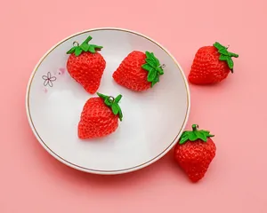Detailed view of realistic PVC strawberries with green leaves and metal key rings