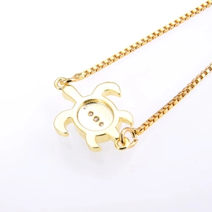 Close-up of a gold turtle pendant with cubic zirconia on a minimalist box chain