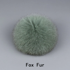 Gros plan d'un pompon en fourrure de renard vert clair montrant la texture douce et naturelle