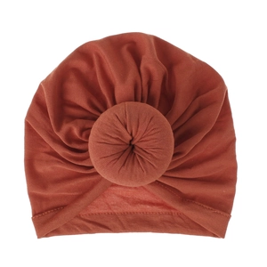 Detailed view of brick red infant turban hat with a bohemian donut knot and soft knit texture