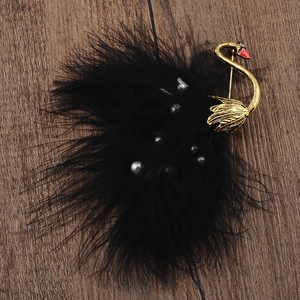Macro shot of swan brooch with black feathers and gold metal on textured wood