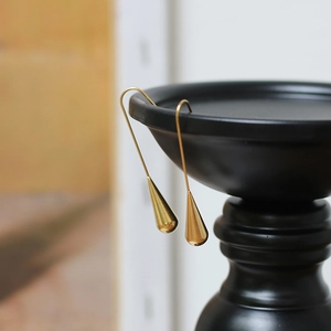 Detail of 18K gold plated teardrop hook earrings with polished mirror finish surface