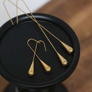 Macro shot of polished gold-plated drop earrings in short and long linear designs
