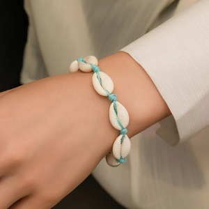 Handmade shell bracelet with natural white cowrie shells and light blue woven rope