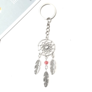 Porte-clés attrape-rêves en métal avec perle rose et pendentifs plumes sur fond blanc pur