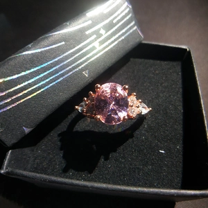 Detailed close-up of rose gold ring with pink oval gemstone in a black velvet box
