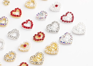 Detail of heart-shaped nail charms with 520 engraving, rhinestones and pearls