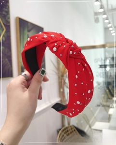 Detail of red knotted headband with sparkling rhinestones and white pearls on fabric
