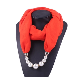 Detail of red chiffon scarf with integrated pearl pendant necklace on a black mannequin