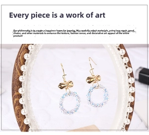 Detail view of lace texture and pearl chain on a white and gold bow earring display