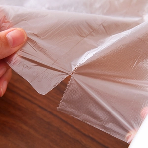 Tear-off roll of transparent PE food storage bags shown in use on a wooden background