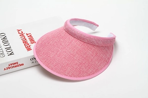 Close-up of pink sun visor with woven texture and wide curved brim on white background