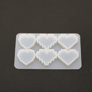 Detail of 6-cavity silicone mold featuring pixel and geometric heart shapes for DIY resin